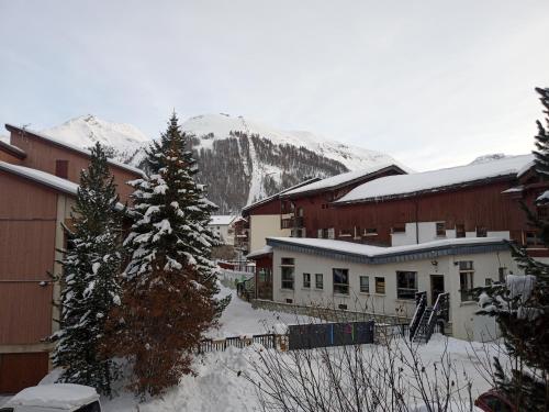 uma cidade coberta de neve com edifícios e uma montanha em Van à louer au pied des pistes em Bourg-Saint-Maurice