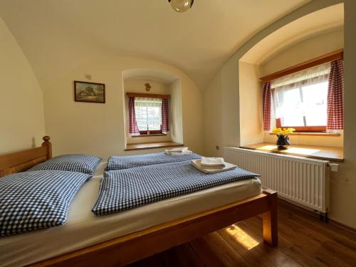 a bedroom with a blue and white bed with two windows at Penzion Stanský Mlýn in Hlinsko