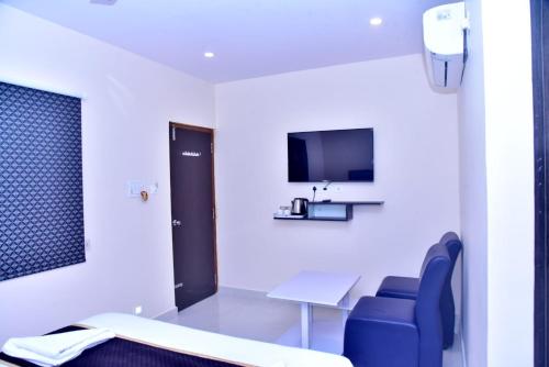 um quarto de hospital com uma mesa e cadeiras e uma televisão em HOTEL PEACOCK INN 