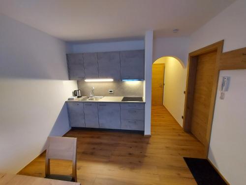 a kitchen with white cabinets and a wooden floor at Appartements Schäfer in San Candido