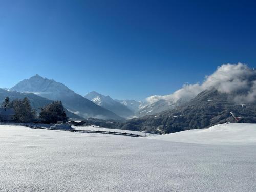 a snow covered field with mountains in the background at Hotel Restaurant Grünwalderhof in Innsbruck
