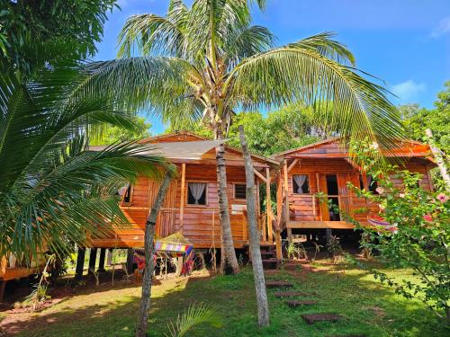 une maison en bois avec des palmiers devant elle dans l'établissement Lighthouse Hotel and Spa, Little Corn island, Nicaragua, à Little Corn Island