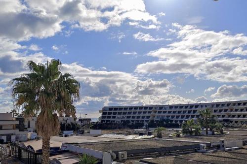 a palm tree in front of a large building at Appartement 204, Natura Beach au village naturiste in Cap d'Agde