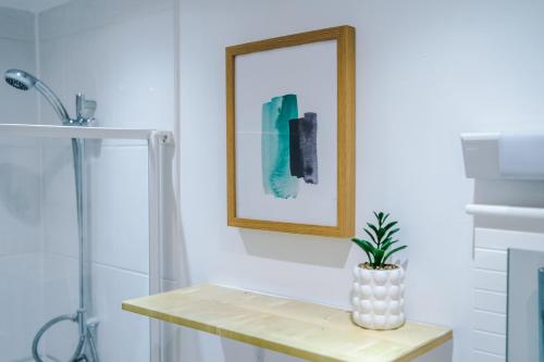 een badkamer met een foto en een plant op een tafel bij The Davidson Serviced Apartment Coventry in Coventry