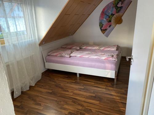 a small bed in a room with a wooden floor at Ferienwohnung nähe Bodensee. in Meckenbeuren