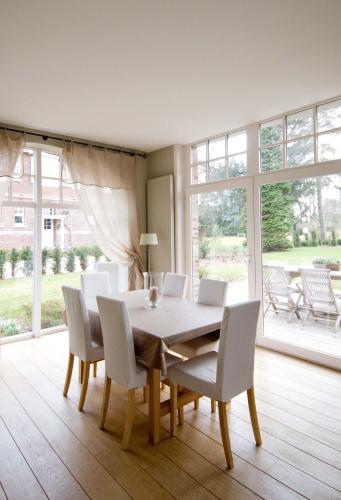 une salle à manger avec une table et des chaises blanches dans l'établissement Gite de charme proche de Lille - La Conciergerie, à Sainghin-en-Mélantois