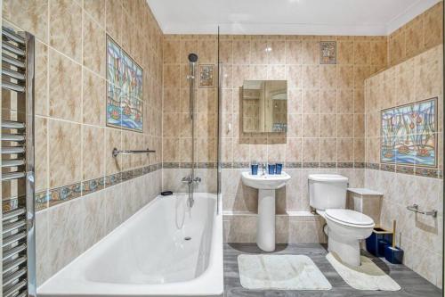 a bathroom with a tub and a toilet and a sink at Luxury Oasis in London