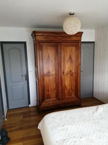 - une chambre avec une armoire en bois à côté d'un lit dans l'établissement Chambre des perdrix, au Mans