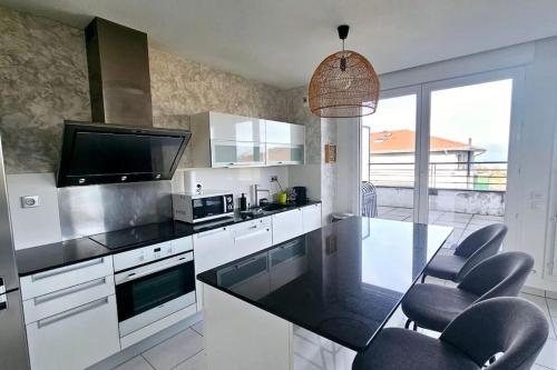 une cuisine avec des armoires blanches et un comptoir noir dans l'établissement Le VacanSciez, à Sciez