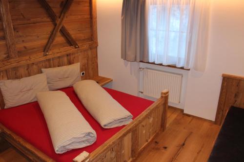 a bedroom with a wooden bed with two pillows on it at Almresidenz Unterrain zum Hartl -1 km BY CAR DISTANCE SKI SLOPES KRONPLATZ in Valdaora