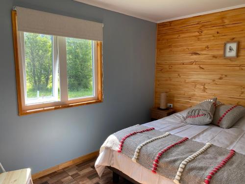 1 dormitorio con 1 cama con pared de madera en Ribera Cochrane, Cochrane, en Cochrane