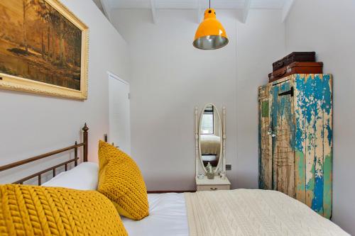 a bedroom with a bed with a yellow blanket and an old refrigerator at Dunes, Waves and Shells - Self Catering Units Langebaan in Langebaan