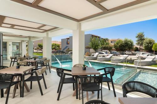 eine Außenterrasse mit Tischen und Stühlen sowie einem Pool in der Unterkunft Elia Agia Marina Resort in Agia Marina