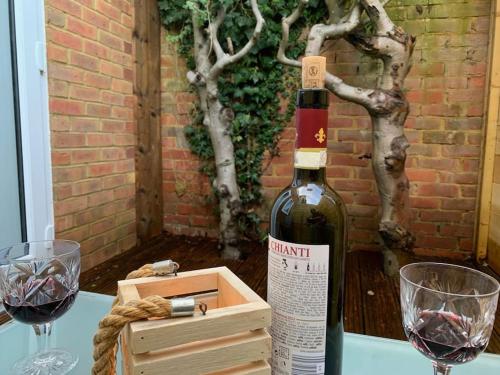 a bottle of wine sitting on a table with two glasses at Annex A, a one bedroom Flat in south London in Carshalton