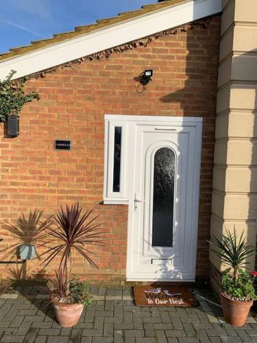 a white door on a brick building with potted plants at Annex A, a one bedroom Flat in south London in Carshalton