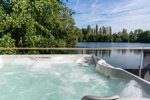 a jacuzzi tub with a view of the water at Camping du Château Vert in Hondainville