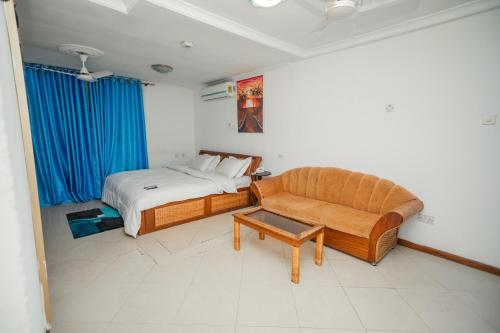 - une chambre avec un lit et un canapé dans l'établissement Beauty Hotel, à Accra