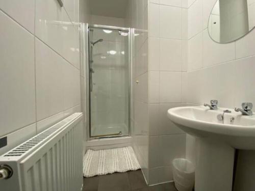 baño blanco con ducha y lavamanos en Spacious Victorian Single Room, en Doncaster