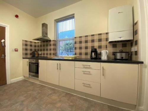a kitchen with white cabinets and a large window at Spacious Victorian Single Room in Doncaster
