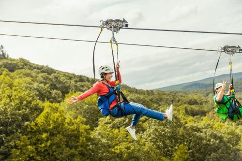 two women zip lining on a zip line in the mountains at Camelback Resort in Tannersville