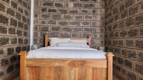 a bed in a room with a brick wall at Babylon Lodge in Marangu