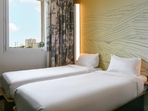 dwa łóżka w pokoju z oknem w obiekcie B&B HOTEL Marseille Prado Vélodrome w Marsylii