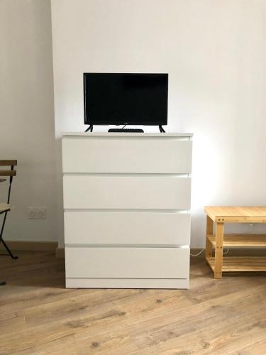 - une commode blanche avec une télévision en haut dans l'établissement Logement neuf, tout confort, au coeur du village, à Saint-Didier