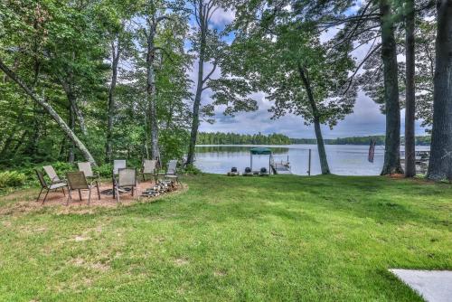 a group of chairs sitting on the grass near a lake at Upper Gresham Lakehouse in Manitowish Waters