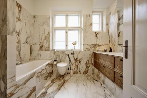 a bathroom with marble walls and a tub and a sink at ApartmentInCopenhagen Apartment 1569 in Copenhagen