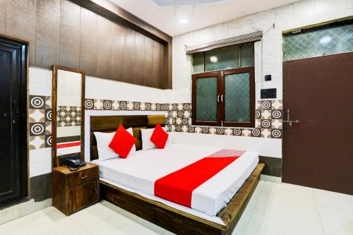 a bedroom with a large bed with red pillows at Flagship Royal Hotel in Kānpur