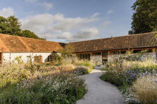 an old barn with a garden in front of it at Lynchets in Dorchester