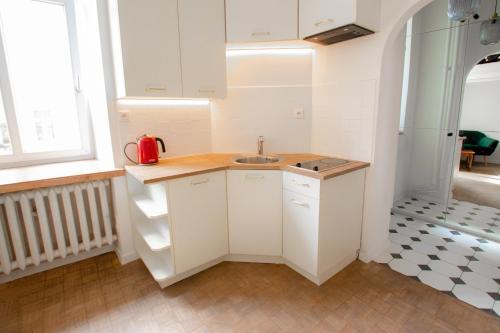 a small kitchen with white cabinets and a sink at Atmospheric studio next to Konecer. Great location in Warsaw