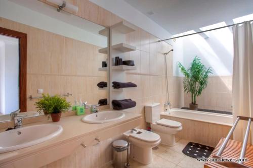 a bathroom with two sinks and a toilet and a tub at Villa Andy Lanzarote in Yaiza