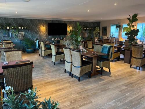 a restaurant with tables and chairs and a flat screen tv at Hotel Pommerscher Hof in Zinnowitz