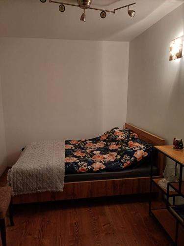 - une chambre avec un lit et une couverture fleurie dans l'établissement Apartament na Przymorzu, à Gdańsk