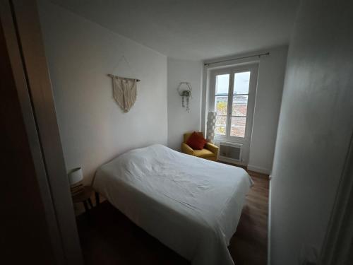 een witte slaapkamer met een bed en een raam bij Cosy appartement lumineux in Arcueil