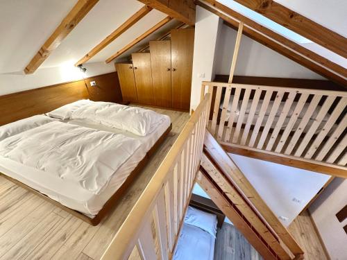 een zolderkamer met een bed op een houten vloer bij Hotel Ferrari in Pinzolo