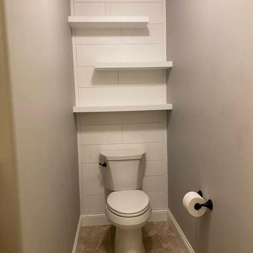 a small bathroom with a white toilet and shelves at Douglas's House in Dublin