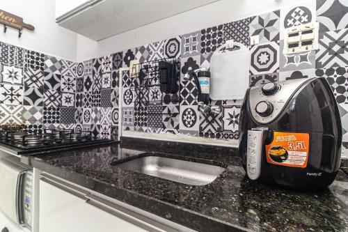 kuchnia z czarno-białymi płytkami na ścianie w obiekcie Apartamento a 140 metros da Praia de Santos w mieście Santos