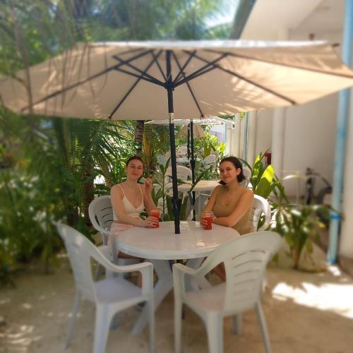 two women sitting at a table under an umbrella at Sunrise Inn in Thoddoo