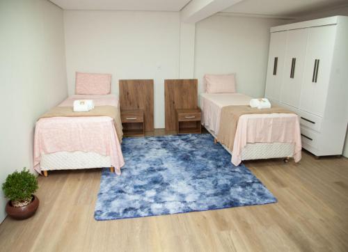 a room with two beds and a blue rug at CM Hotel in Ribas do Rio Pardo