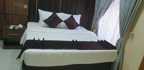 a bedroom with a large bed with white sheets and brown pillows at Davina Hill resort & hotel in Gwarinpa