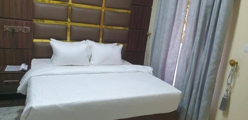 1 cama con sábanas blancas y almohadas en una habitación en Davina Hill resort & hotel en Gwarinpa
