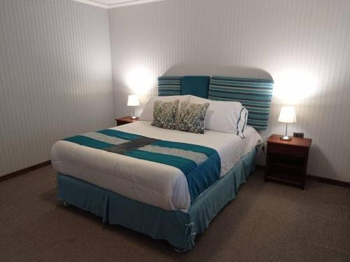 1 dormitorio con 1 cama grande con sábanas azules y blancas en Acogedora cabaña en el campo. Cerca de la ciudad., en Villarrica