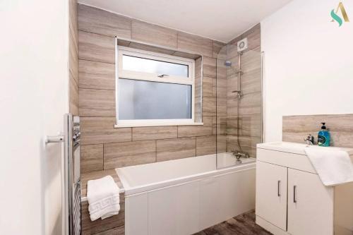 een badkamer met een bad, een wastafel en een raam bij Everett House in Hartlepool