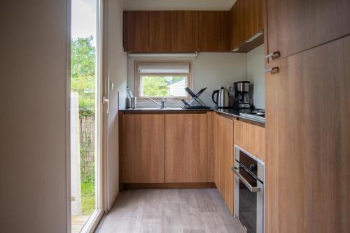 a small kitchen with wooden cabinets and a window at Camping du Château Vert in Hondainville