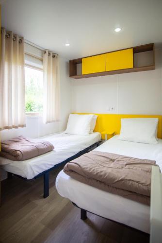 a room with two beds and a window at Camping du Château Vert in Hondainville