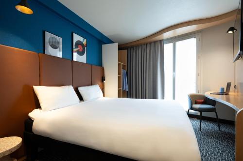 una camera d'albergo con un grande letto e una scrivania di ibis Paris Gare de Lyon Reuilly a Parigi