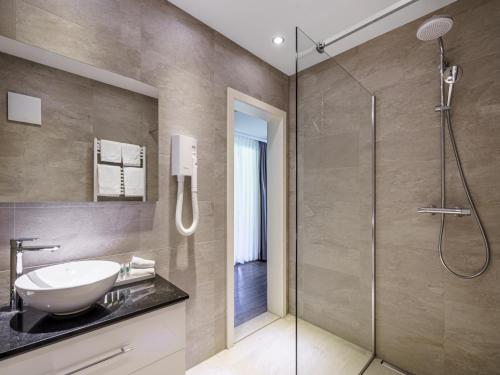 La salle de bains est pourvue d'un lavabo et d'une douche. dans l'établissement Hotel Seeburg - Adults only, à Ringgenberg