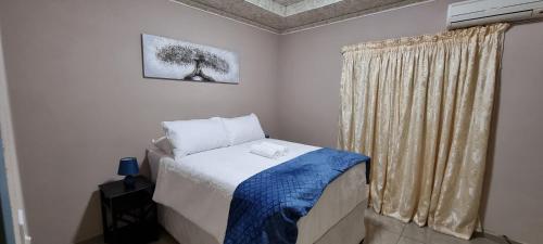 Sapphire Lodge في Siteki: غرفة نوم صغيرة بها سرير ونافذة